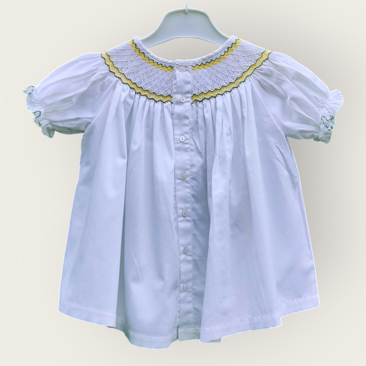 Blouse blanche smockée, réversible. Détails jaune et vert.